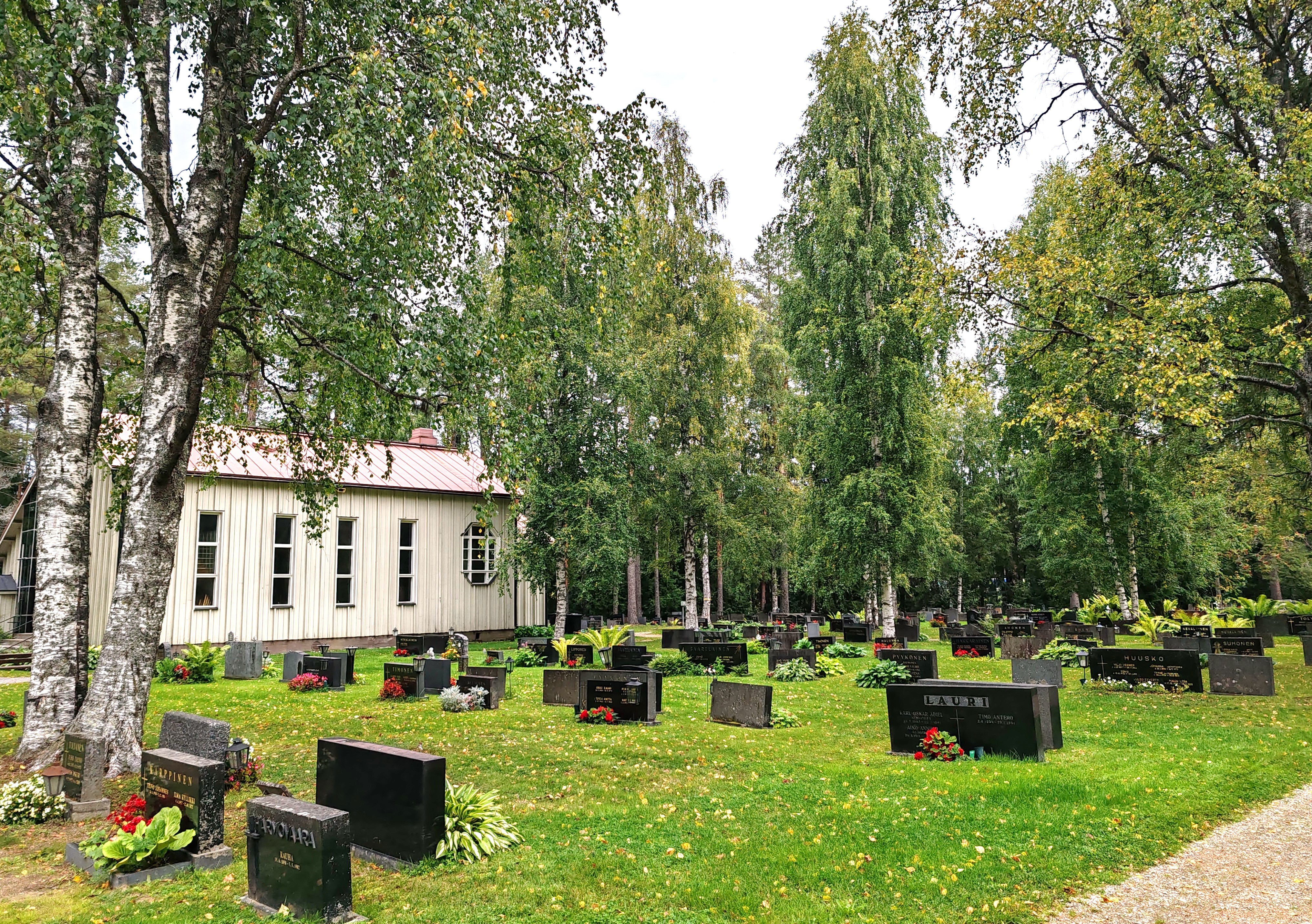 Valtimon hautausmaa Kuvassa puinen rakennus ja erilaisia hautakiviä. Valtimon hautausmaa.